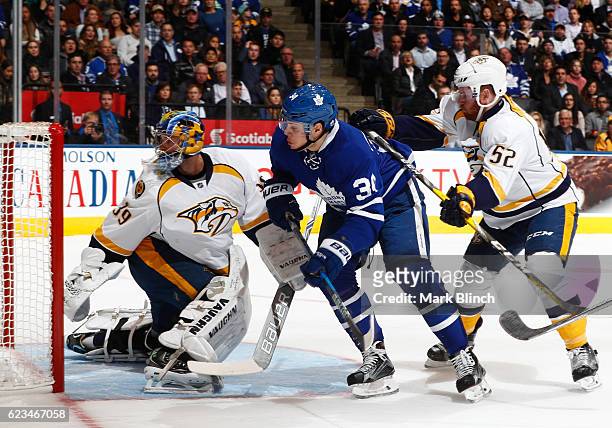 Auston Matthews of the Toronto Maple Leafs follows the puck with Matt Irwin and goalie Marek Mazanec of the Nashville Predators during the first...