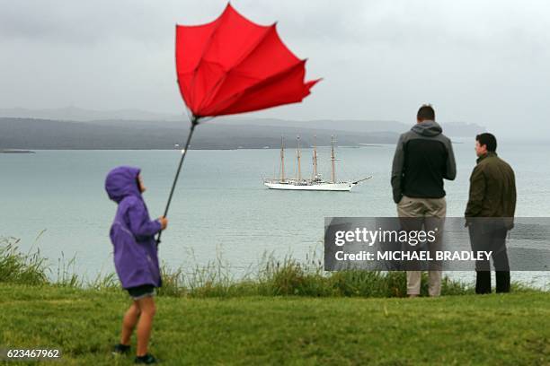 Child struggles with an umbrella as people watch the Bach Esmerelda from Chile arrive into the Waitemata Harbour as part of the fleet entry to...