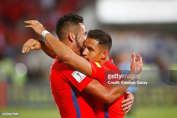 Alexis Sanchez of Chile celebrates with teammate Mauricio Isla after scoring the third goal of his team during a match between Chile and Uruguay as a...