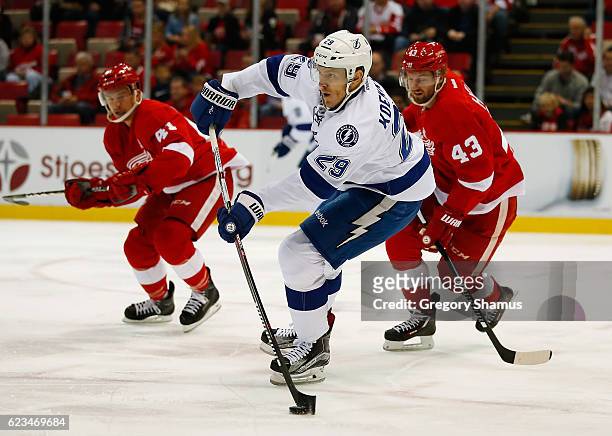 Slater Koekkoek of the Tampa Bay Lightning passes to a teammate in front of Darren Helm and Luke Glendening of the Detroit Red Wings at Joe Louis...