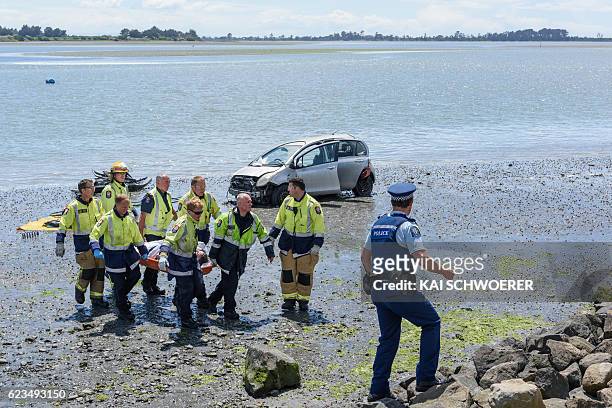 Emergency services carry an injured man from the scene where a man crashed his car into the sea on November 16, 2016 in Christchurch, New Zealand. A...