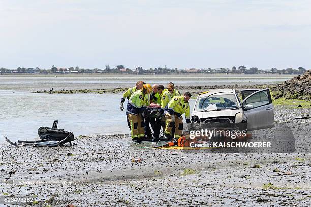 Emergency services carry an injured man from the scene where a man crashed his car into the sea on November 16, 2016 in Christchurch, New Zealand. A...