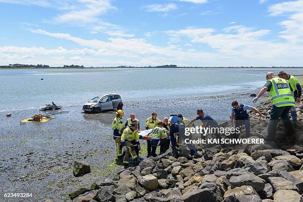 Emergency services carry an injured man from the scene where a man crashed his car into the sea on November 16, 2016 in Christchurch, New Zealand. A...