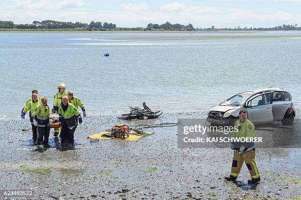 Emergency services carry an injured man from the scene where a man crashed his car into the sea on November 16, 2016 in Christchurch, New Zealand. A...