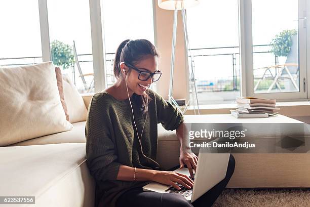 happy young woman using her laptop at home - ado latino stock pictures, royalty-free photos & images