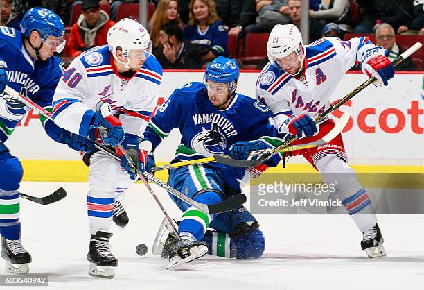 Derek Stepan and Michael Grabner of the New York Rangers combine to check Michael Chaput of the Vancouver Canucks during their NHL game at Rogers...