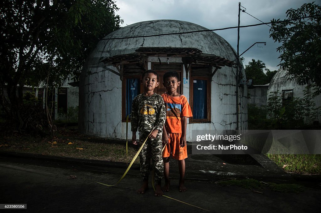 Azra Putra (L) and Fale Juan (6) pose in front of dome home in New Ngelepen village, Yogyakarta, Indonesia on November 14, 2016