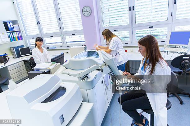 three cute technicians in laboratory of blood bank - blood bank stock pictures, royalty-free photos & images