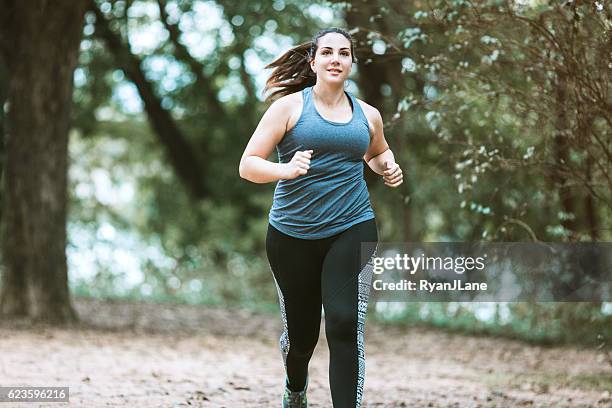 woman running in park - zware lichaamsbouw stockfoto's en -beelden