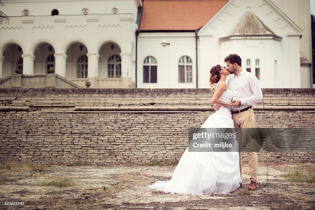 Happy newlyweds standing in front of old castle