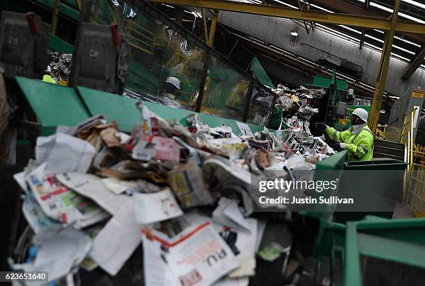 Workers sort recyclable materials as they pass through a sorting machine at Recology's Recylce Central on November 16, 2016 in San Francisco,...