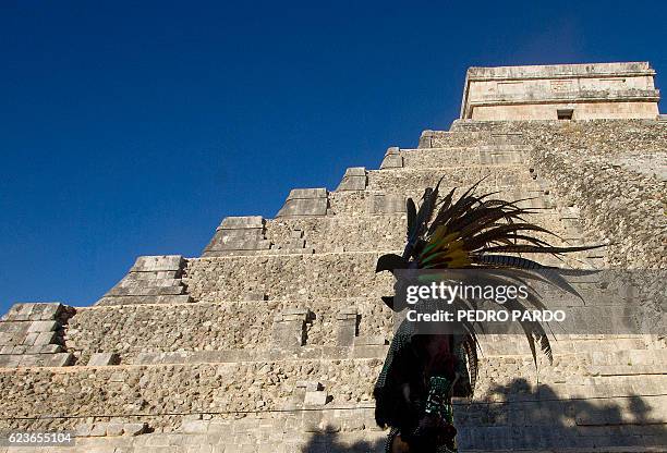 Mexican man wearing a pre-hispanic costume walk next to the Kukulkan pyramid at the Chichen Itza archaeological park, in Yucatan state, Mexico on...