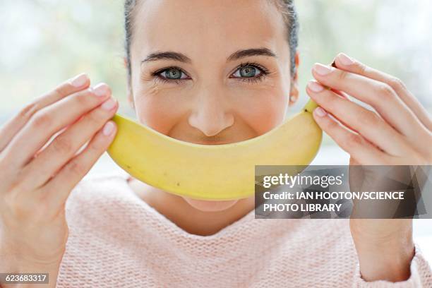 woman holding a banana in front of face - banana woman stock pictures, royalty-free photos & images