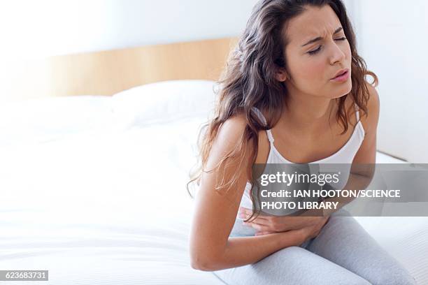 woman on bed with cramps - sindrome premestruale foto e immagini stock