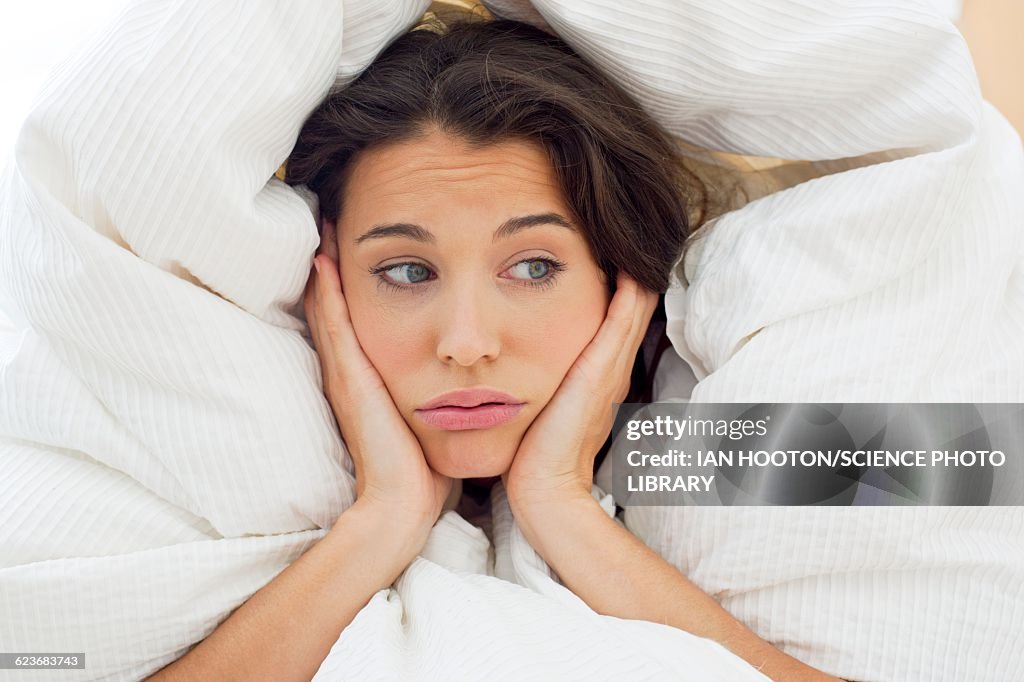 Woman in bed with hands on chin