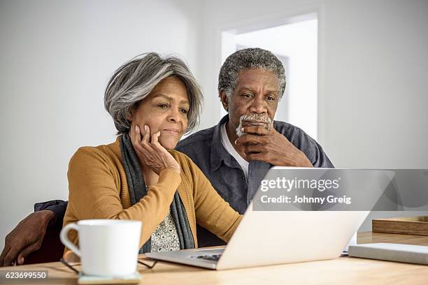 pareja afroamericana de la tercera edad usando la computadora portátil, contemplando - contemplation couple fotografías e imágenes de stock
