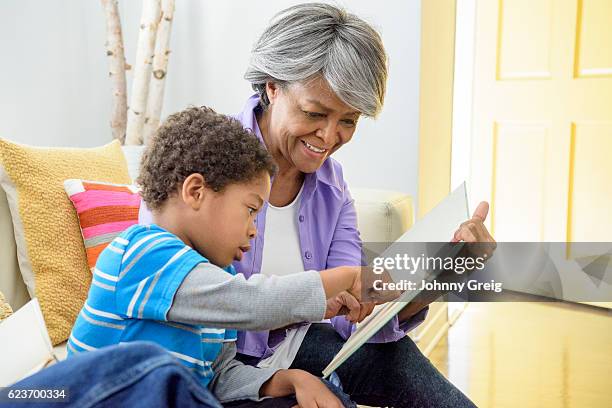 african american grandmother showing book to grandson, smiling - reading old young stock pictures, royalty-free photos & images