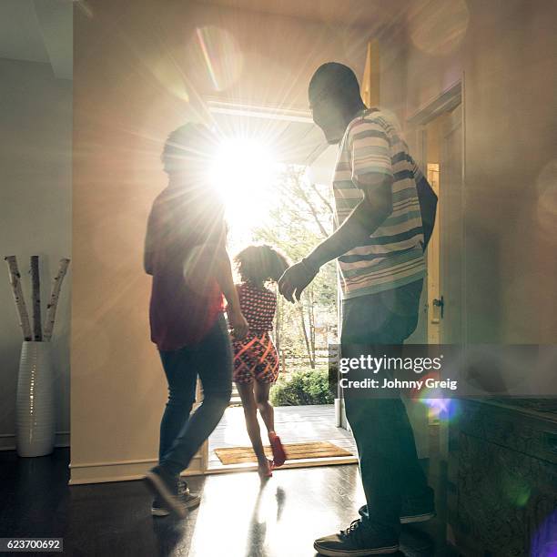 parents with daughter leaving  the house in bright sunlight - man opening door woman bildbanksfoton och bilder