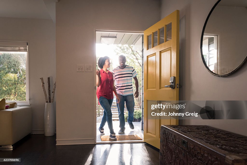 African American couple arriving home in doorway, smiling