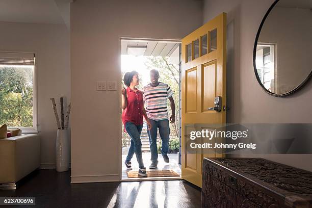 african american couple arriving home in doorway, smiling - happy arrival stock pictures, royalty-free photos & images