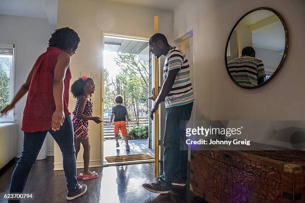 familia afroamericana saliendo de la casa, padre sosteniendo la puerta - open day 4 fotografías e imágenes de stock