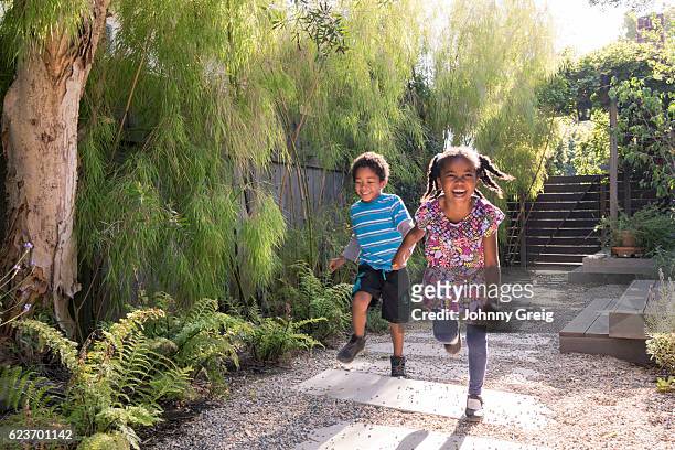 carefree children running and playing in garden - lane sisters stockfoto's en -beelden