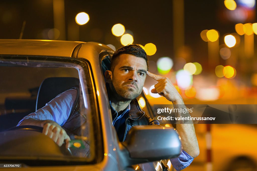 Angry young man driving car at night