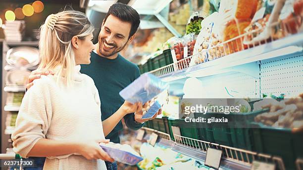 couple shopping in supermarket. - picking up groceries stock pictures, royalty-free photos & images