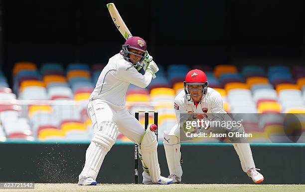 Queensland's Usman Khawaja plays a shot as Alex Carey looks on during day one of the Sheffield Shield match between Queensland and South Australia at...