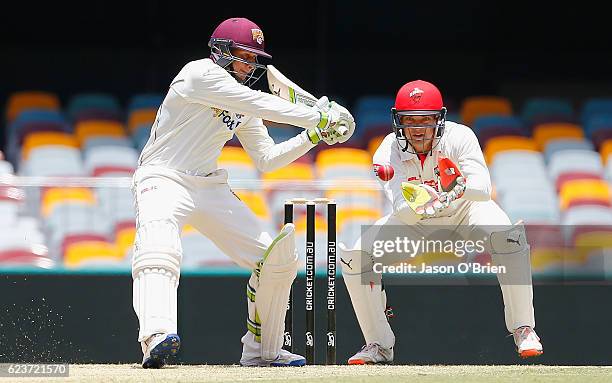 Queensland's Usman Khawaja plays a shot as Alex Carey looks on during day one of the Sheffield Shield match between Queensland and South Australia at...