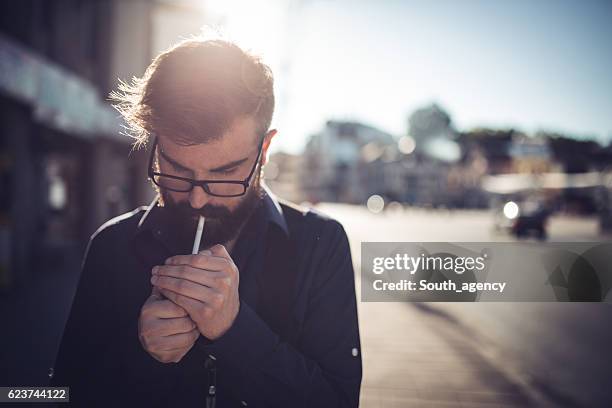 hipster lighting a cigarette - tobacco workers stockfoto's en -beelden