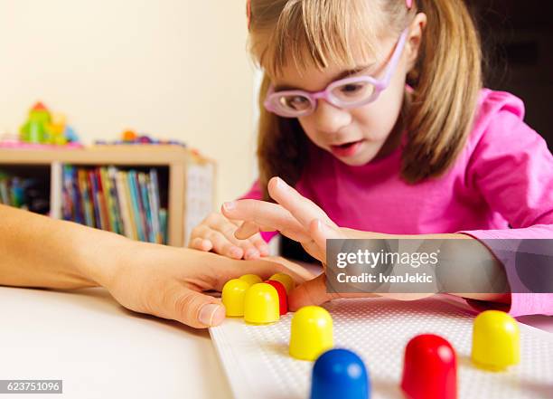 child playing with mosaic peg board with teacher - blindheid stockfoto's en -beelden