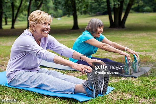 mujeres mayores sonrientes haciendo ejercicio en clase de yoga - hands in her pants fotografías e imágenes de stock
