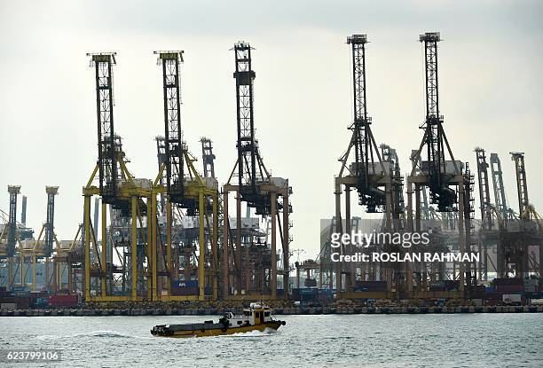 Boat passes in front of cranes at Tanjong Pagar container port in Singapore on November 17, 2016. Singapore's exports fell more than expected in...
