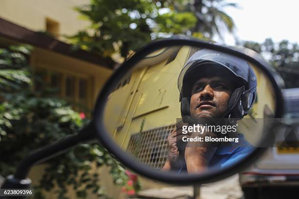 Abdul Saleem, a deliveryman known as a Wishmaster for Flipkart Online Services Pvt's Ekart Logistics service, putting on his helmet is reflected in...