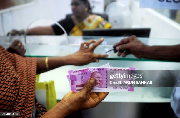 An Indian woman displays her 2000 rupee notes as she has her finger inked with indelible ink after exchanging withdrawn 500 and 1000 rupee banknotes...