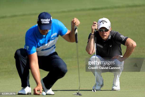 Danny Willett of England who is leading the European Tour 'Race to Dubai' lines up his putt behind Henrik Stenson of Sweden who is currently second...
