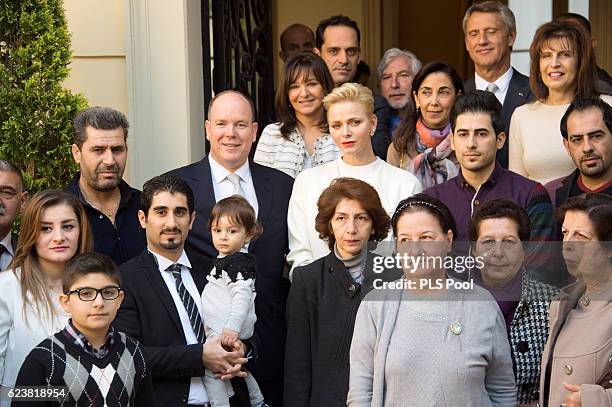 Prince Albert II of Monaco and Princess Charlene of Monaco pose with refugees during the Parcels Distribution At Monaco Red Cross Headquarters on...