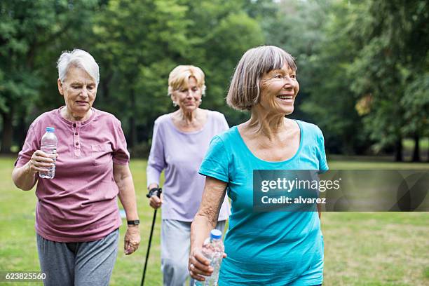 healthy senior women walking in park - senior women group stock pictures, royalty-free photos & images