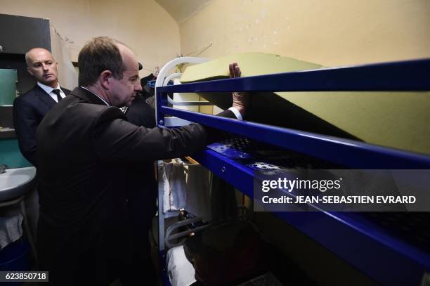 French Justice Minister Jean-Jacques Urvoas raises a mattress in an inmate's cell as he visits the prison of Angers, western France on November 17,...