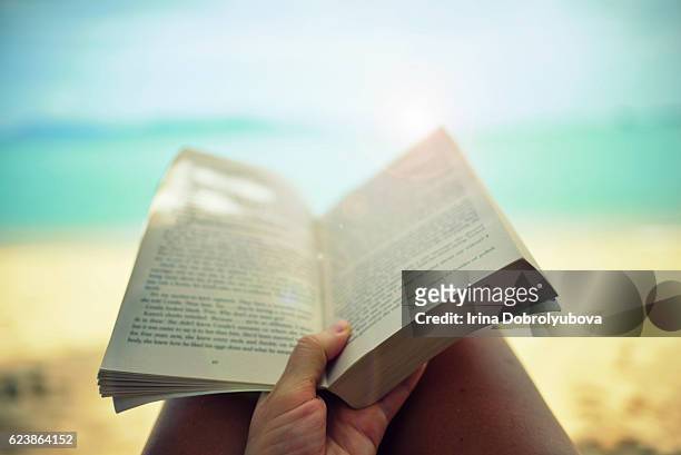 reading paper book on the beach from personal perspective - beach book reading stock-fotos und bilder