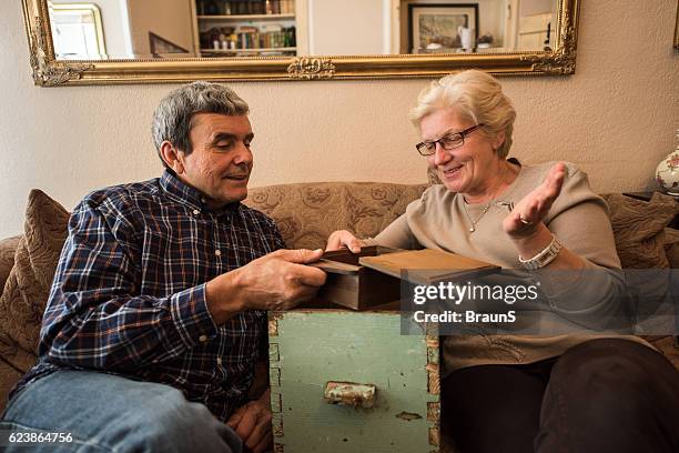 smiling senior couple evoking their memories at home. - memories box stock pictures, royalty-free photos & images