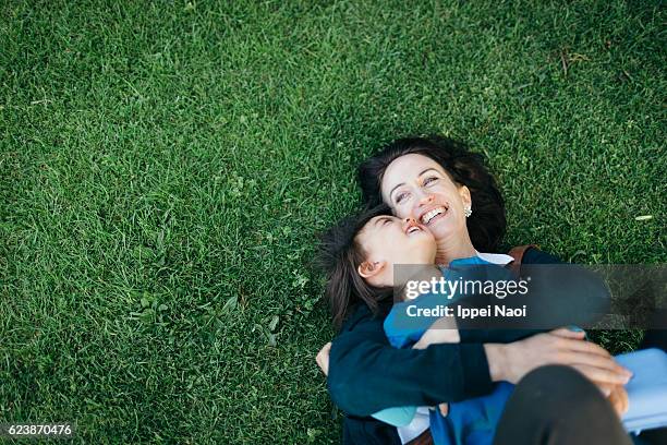 mother and child lying on grass and cuddling - family in garden imagens e fotografias de stock