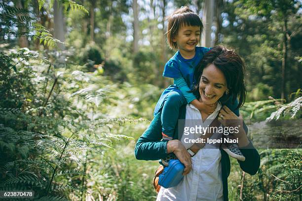 mother hiking with her child in forest, australia - piggyback stock pictures, royalty-free photos & images