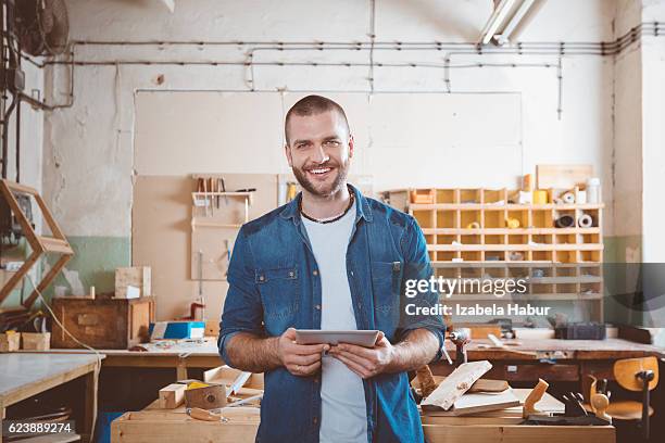 junger mann in einer schreinerei - smiling professional at work tools stock-fotos und bilder