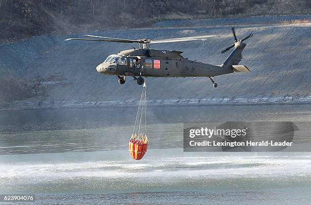 Kentucky National Guard Blackhawk helicopter fills a 660 gallon bucket with water from a coal mine pond, to drop on a nearby forest fire on Thursday,...