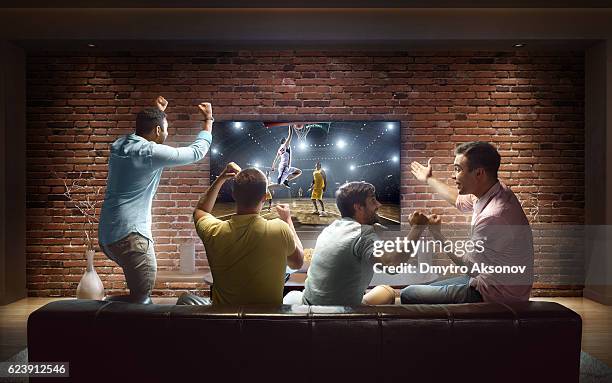 students watching basketball game at home - man watching tv on couch stockfoto's en -beelden