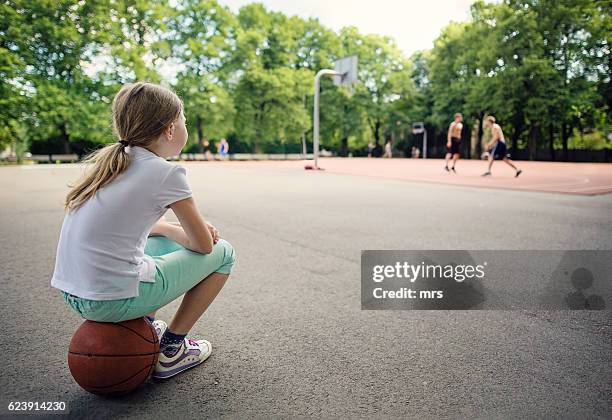 girl sitting on basketball, waiting to play - child alone stockfoto's en -beelden