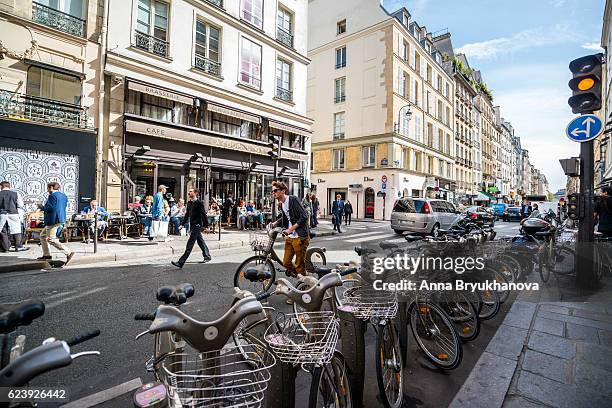 paris street with bicycles parked and people in a cafe - parked car stock pictures, royalty-free photos & images