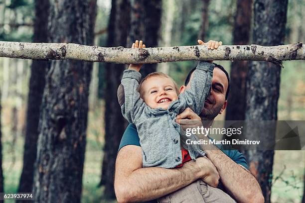 vater und sohn spielen zusammen - eltern baby hochheben stock-fotos und bilder